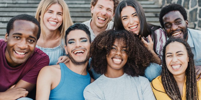 Young group of people smiling on camera having fun outdoor in the city - Focus on african girl face